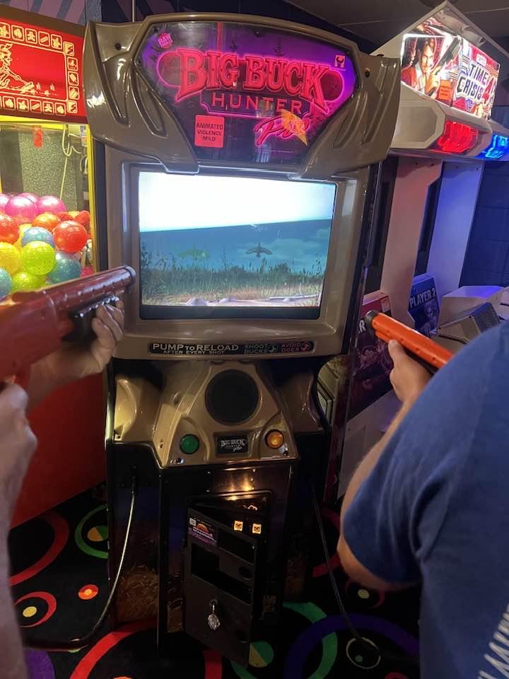 Guests playing arcade shooter games next to a claw machine at a local venue